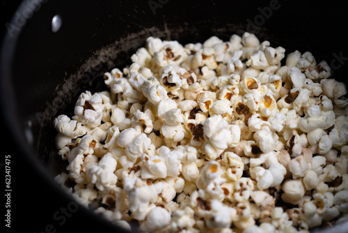 Close up of Puffed light golden popcorns on dark wooden serving tray