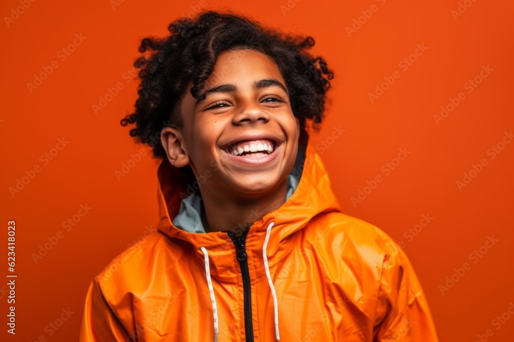 Medium shot portrait photography of a grinning boy in his 30s wearing a lightweight windbreaker against a bright orange background. With generative AI technology