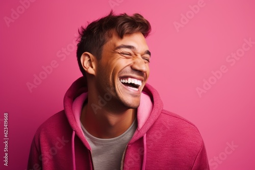 Close-up portrait photography of a joyful boy in his 30s wearing a cozy sweater against a hot pink background. With generative AI technology