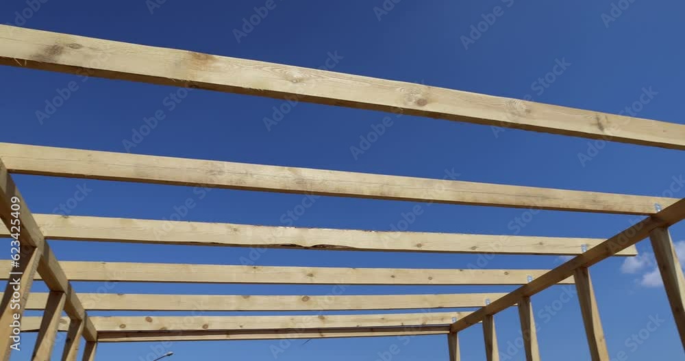 wooden beams used during the construction of the frame of the building, the manufacture of a new building using wood, against the blue sky wooden beams used during the construction of the frame of the building, the manufacture of a new building using wood, against the blue sky