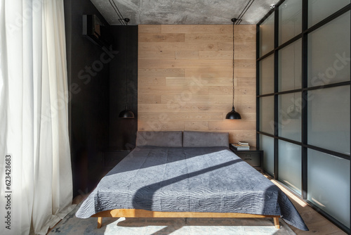Photography Comfortable double bed with bedcover against wooden wall in bedroom