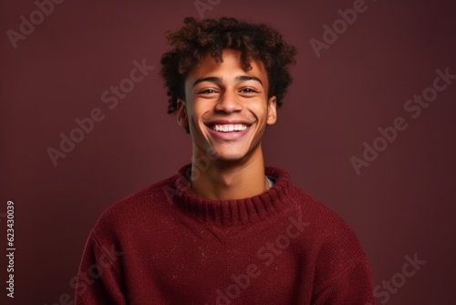Medium shot portrait photography of a satisfied boy in his 20s wearing a cozy sweater against a rich maroon background. With generative AI technology © Markus Schröder