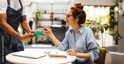 Foto NFC payment: Woman paying a bill with her smartphone in a cafe