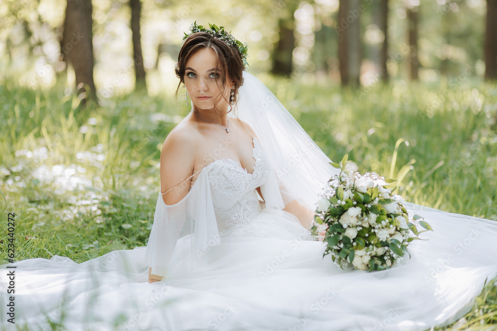 a beautiful bride in a white dress with a wreath of fresh flowers is sitting on the green grass a beautiful bride in a white dress with a wreath of fresh flowers is sitting on the green grass