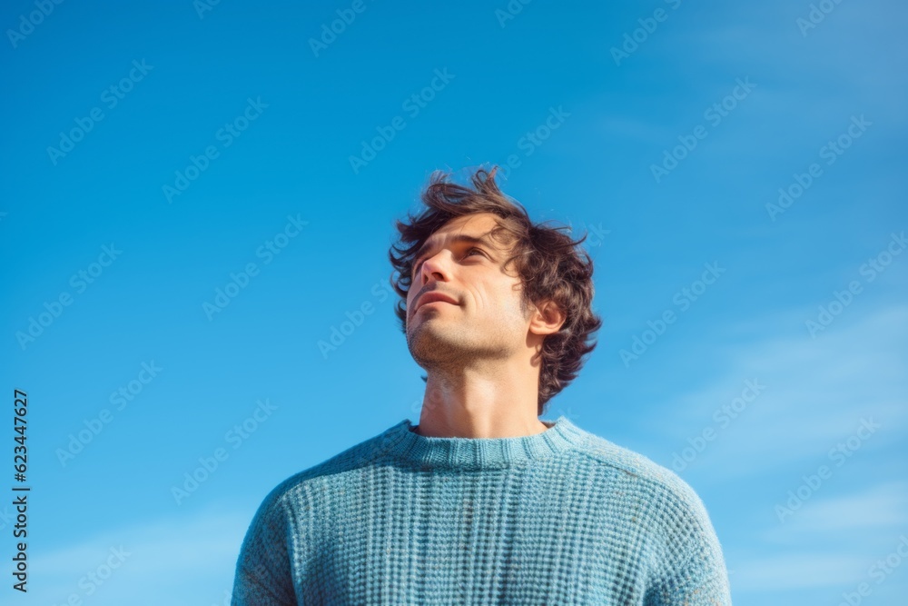 Conceptual portrait photography of a beautiful boy in his 30s wearing a cozy sweater against a sky-blue background. With generative AI technology Conceptual portrait photography of a beautiful boy in his 30s wearing a cozy sweater against a sky-blue background. With generative AI technology