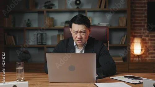 Young businessman feeling pissed of because of getting negative result and failing project at comfy workplace. Upset asian worker desperately closing personal laptop and crossing hands.