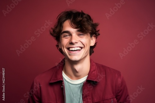 Medium shot portrait photography of a happy boy in his 30s wearing a denim jacket against a burgundy red background. With generative AI technology © Markus Schröder
