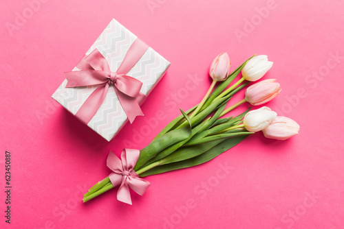 Φωτογραφία Pink tulips flowers and gift or present box on colored table background