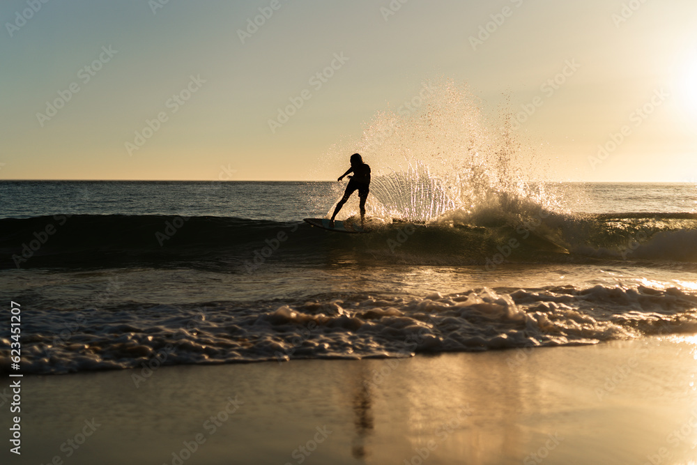 Figura silueta de chico haciendo surf en la orilla de la playa