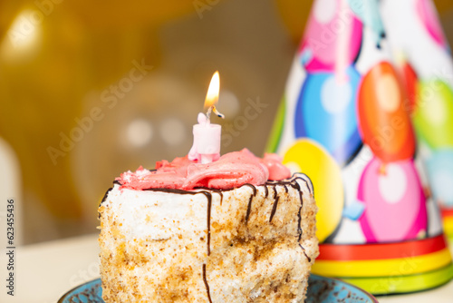 A small piece of cake with a burning birthday candle.