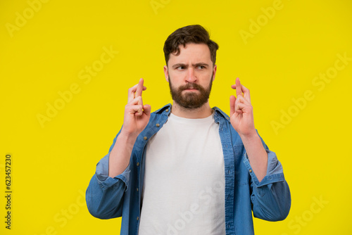 Young man posing with crossed fingers and serious face expression
