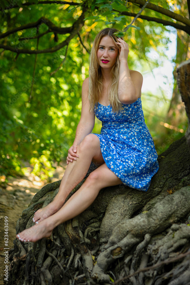 woman in a blue dress on a tree root woman in a blue dress on a tree root