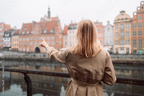 Attractive young stylish blonde woman walking the street Krakow, Poland with smartphone in hands. High quality photo