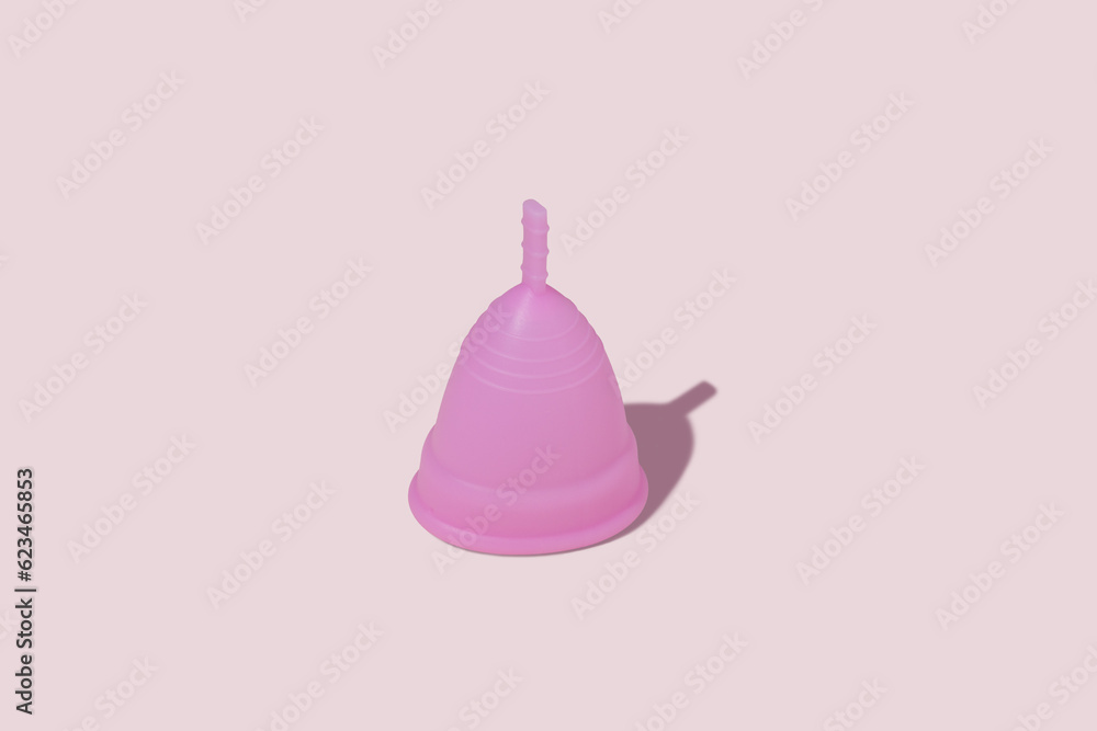 Pink reusable silicone menstrual cup on pink background. Concept of feminine hygiene, gynecology and health Pink reusable silicone menstrual cup on pink background. Concept of feminine hygiene, gynecology and health