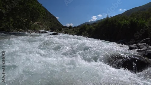 Small mountain river with crystal clear water. Water flows over the stones overgrown photo