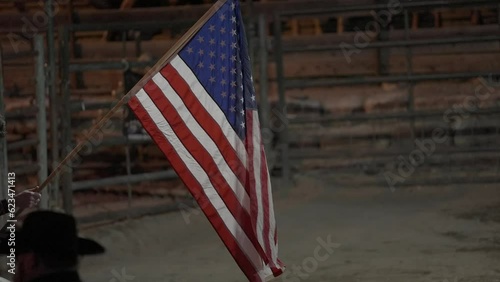 This video shows an American flag blowing in the wind in slow motion at a rodeo event.