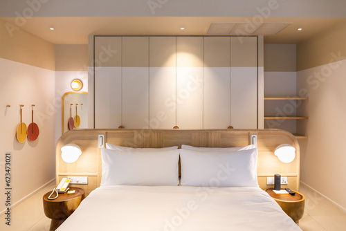 White bed and pillows in a room with decorative plants and warm lighting.