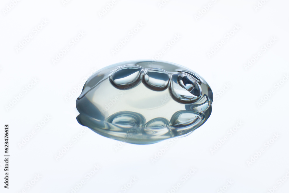 A drop of clear gel with bubbles. On a white background. With reflection in the mirror A drop of clear gel with bubbles. On a white background. With reflection in the mirror