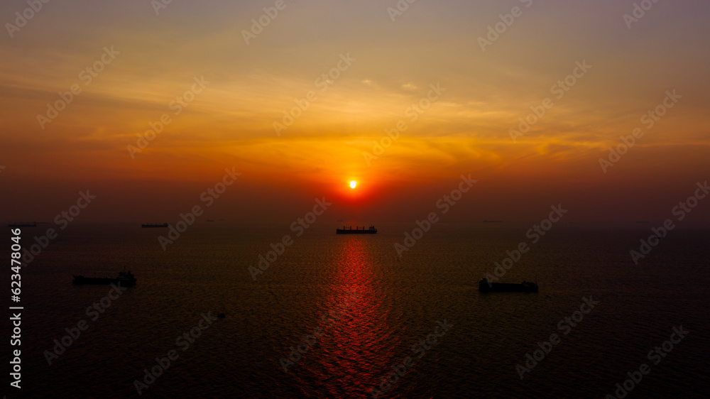 Seascape and silhouette container ship floating in sea and over the sunlight background