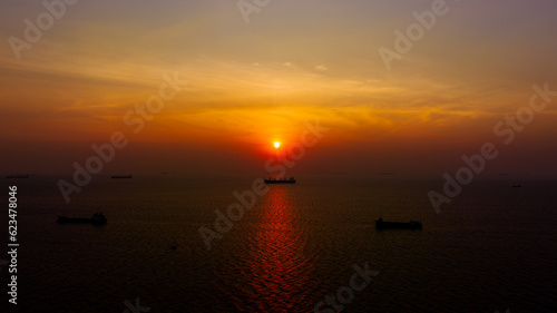 Seascape and silhouette container ship floating in sea and over the sunlight background © SHUTTER DIN