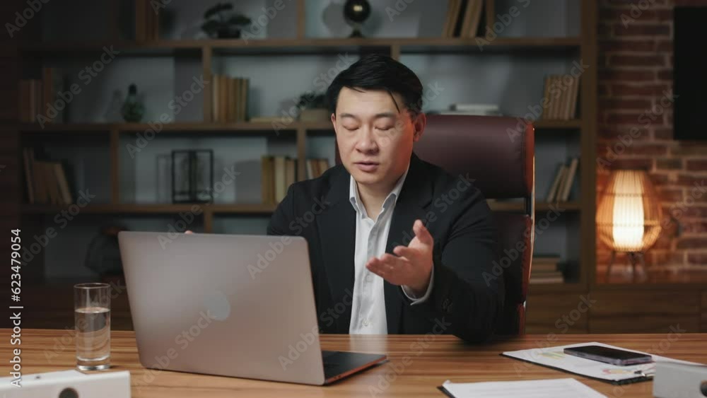 Sales manager participating in video meeting with teammates and sharing ideas regarding new business startup. Successful asian gentleman discussing international trade market using portable device. Sales manager participating in video meeting with teammates and sharing ideas regarding new business startup. Successful asian gentleman discussing international trade market using portable device.