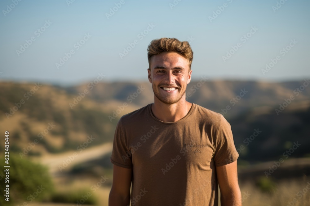Sports portrait photography of a happy boy in his 30s wearing a casual t-shirt against a rolling hills background. With generative AI technology