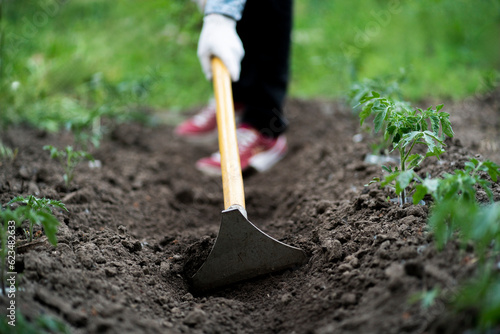 Foto cultivating the soil in the garden, young male doing work using a hoe