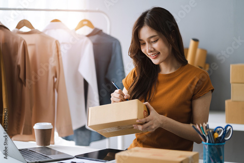 Schilderij op canvas Woman start up small business owner writing address on cardboard box at workplace