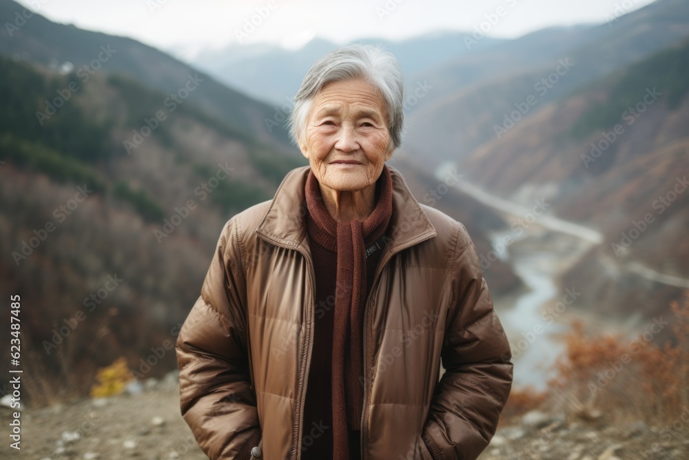 Environmental portrait photography of a tender old woman wearing a sleek bomber jacket against a scenic mountain trail background. With generative AI technology