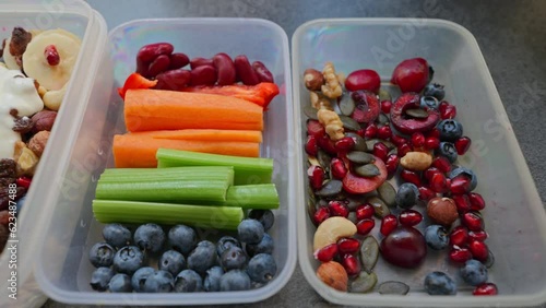 Boxes with healthy food full of colorful vegetables and fruits. Nuts, blueberries, yogurt, pomegranates, bananas, gluten-free pancakes, raisins, celery, carrots and peppers. Meals for the day. 