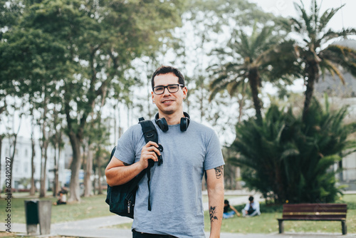 Portrait of young student with glasses and backpack in an outdoor park. Concept of people.