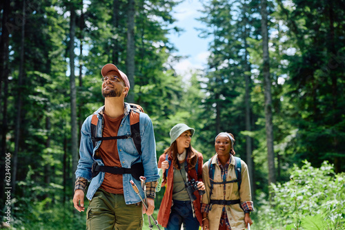 Canvas Print Happy backpacker and his friends hiking in forest.
