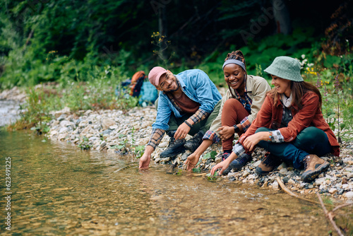 Group of happy of hikers have fun by clean water of mountain spring.