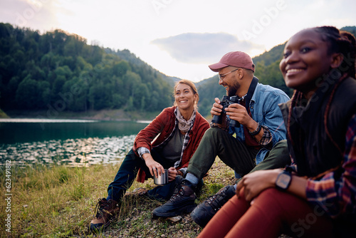 Group of young happy friends relaxing by lake in nature. © Drazen