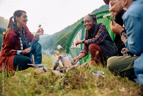 фотографія Young happy hikers roasting marshmallows on camping day in nature
