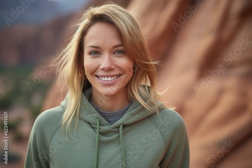 Lifestyle portrait photography of a happy girl in her 30s wearing a comfortable hoodie against a scenic canyon background. With generative AI technology © Markus Schröder