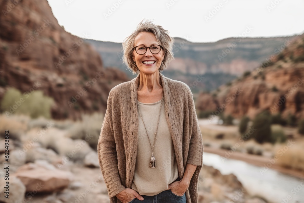 Lifestyle portrait photography of a glad mature girl wearing a chic cardigan against a scenic canyon background. With generative AI technology