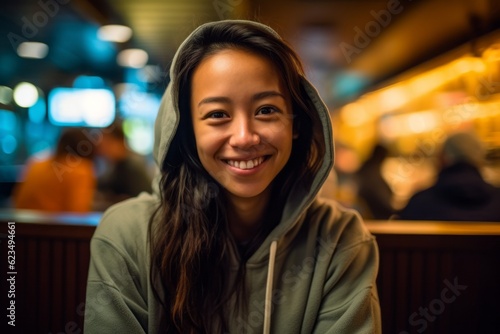 Close-up portrait photography of a joyful girl in her 30s wearing a cozy zip-up hoodie against a bustling cafe background. With generative AI technology