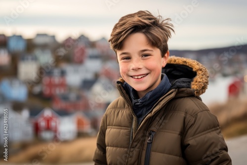 Editorial portrait photography of a happy mature boy wearing a cozy winter coat against a scenic coastal village background. With generative AI technology
