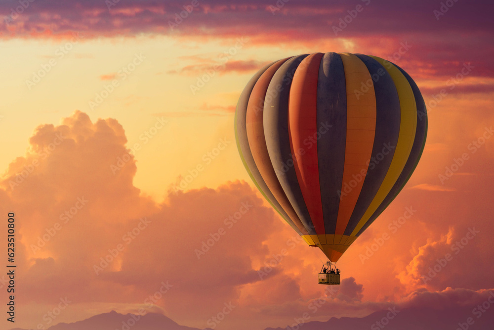 Obraz premium A hot air balloon rising under partly cloudy skies during a brillant sunset with lots of color.