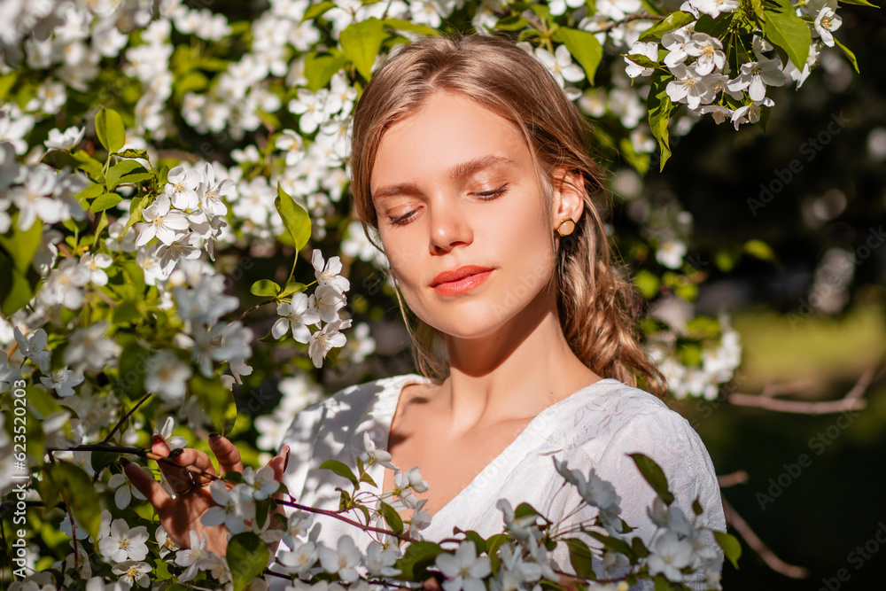 Portrait of a girl in a white dress in blooming apple trees. The girl poses against the background of flowers in the spring park. Portrait of a girl in a white dress in blooming apple trees. The girl poses against the background of flowers in the spring park.