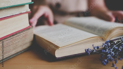 a girl in a vintage dress sits at a table and reads a book. Girl turning the pages, reading a novel in an old library