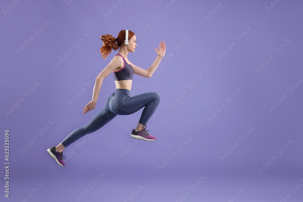 Woman in sportswear jumping on violet background, space for text