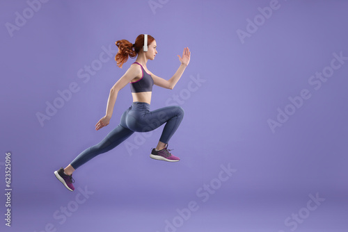 Woman in sportswear jumping on violet background, space for text