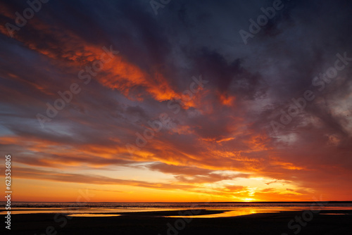 sunset sky with reflections in water, sunlight and colored orange clouds. Magnificent view of the sea and sun in evening. travel and freedom, meditation, poster. amazing sunset light on ocean