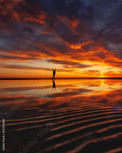 silhouette person against background beautiful sunset sky on ocean, reflection rays sun and sky in water. Freedom inspiration in nature under open sky enjoys beautiful view and meditates, happiness