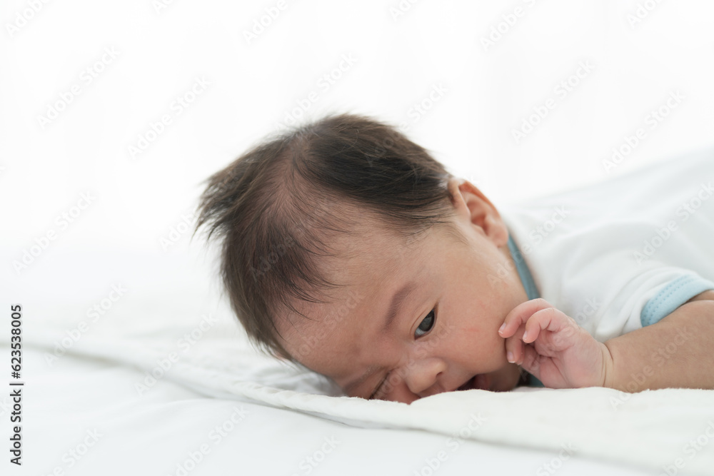 Newborn baby sleeping on blanket on white bed. Infant lying on white bed. Asian newborn baby sleeping in prone position. Asian infant Newborn baby sleeping on blanket on white bed. Infant lying on white bed. Asian newborn baby sleeping in prone position. Asian infant