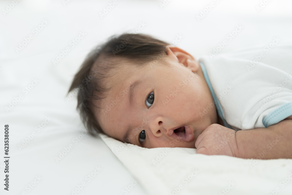 Newborn baby sleeping on blanket on white bed. Infant lying on white bed. Asian newborn baby sleeping in prone position. Asian infant Newborn baby sleeping on blanket on white bed. Infant lying on white bed. Asian newborn baby sleeping in prone position. Asian infant