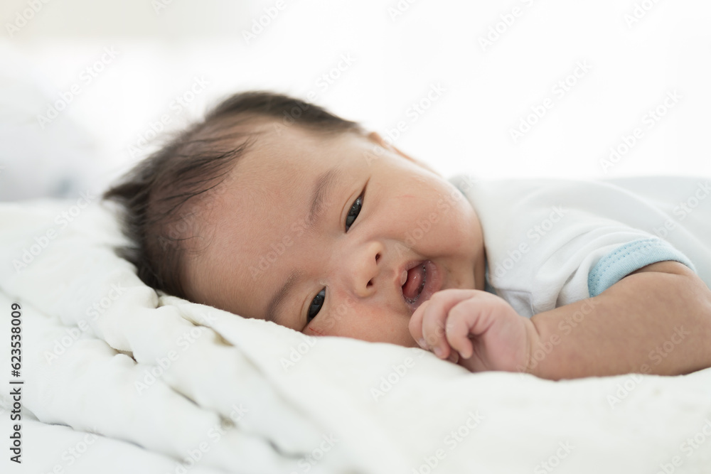 Newborn baby sleeping on blanket on white bed. Infant lying on white bed. Asian newborn baby sleeping in prone position. Asian infant Newborn baby sleeping on blanket on white bed. Infant lying on white bed. Asian newborn baby sleeping in prone position. Asian infant