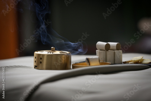 Moxibustion treatment - traditional Chinese medicine tools for acupuncture points heating therapy. Chinese herbal medicine. Moxibustion copper burner box with moxa herbal sticks in holistic spa. photo